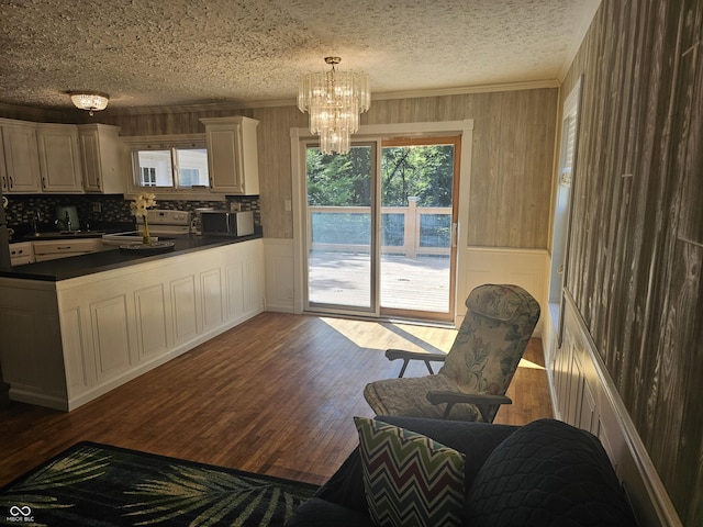 1317 S Ebert Dr, Rockville, IN 47872 - kitchen featuring dark countertops, crown molding, a chandelier, stainless steel microwave, and dark wood-style floors