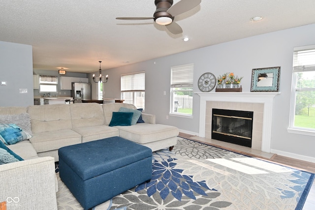 15524 Follow Dr, Noblesville, IN 46060 - living area featuring a chandelier, a ceiling fan, a tiled fireplace, a textured ceiling, and recessed lighting