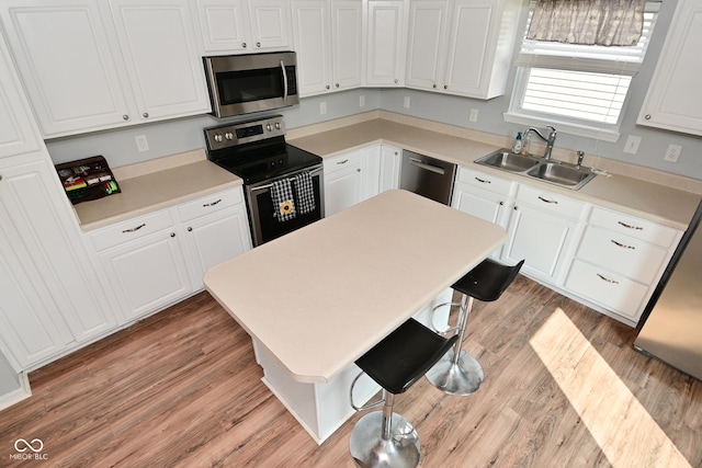 15524 Follow Dr, Noblesville, IN 46060 - kitchen with appliances with stainless steel finishes, a sink, white cabinets, a breakfast bar area, and light countertops