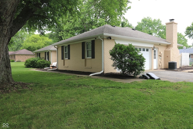 3119 W Burning Tree Rd, Crawfordsville, IN 47933 - view of side of property with a garage, brick siding, a chimney, asphalt driveway, and a lawn
