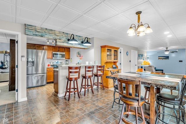 101 Jefferson Vly, Coatesville, IN 46121 - kitchen featuring appliances with stainless steel finishes, brown cabinetry, ceiling fan, a breakfast bar, and a peninsula