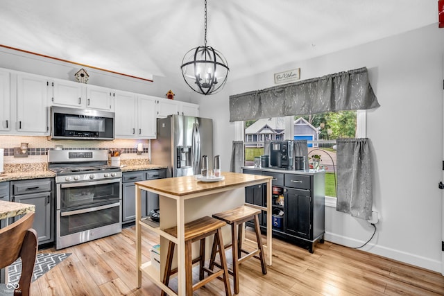 101 Jefferson Vly, Coatesville, IN 46121 - kitchen with appliances with stainless steel finishes, a chandelier, backsplash, light wood-type flooring, and pendant lighting