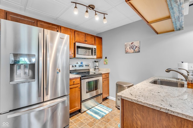 101 Jefferson Vly, Coatesville, IN 46121 - kitchen featuring appliances with stainless steel finishes, brown cabinetry, light stone counters, and track lighting