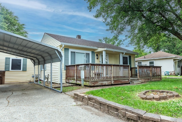 2620 13th St, Columbus, IN 47201 - ranch-style home featuring a carport, concrete driveway, a front yard, an outdoor fire pit, and a chimney