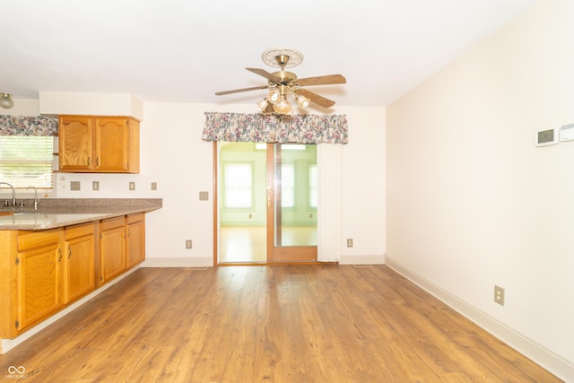 391 W 500 S, Anderson, IN 46013 - kitchen featuring a ceiling fan, light wood-style floors, brown cabinetry, and light stone counters