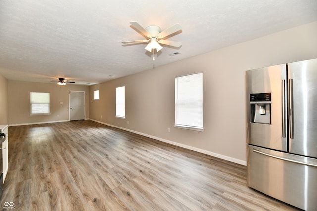 2026 Spruce St, Indianapolis, IN 46203 - unfurnished living room with ceiling fan, light wood-type flooring, baseboards, and a textured ceiling