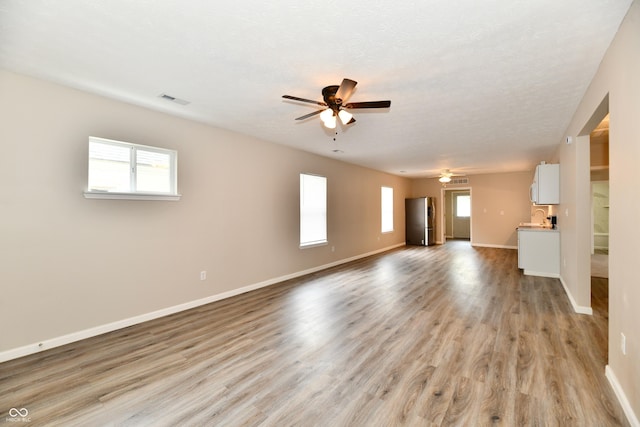 2026 Spruce St, Indianapolis, IN 46203 - unfurnished living room with ceiling fan, baseboards, light wood-style floors, and a sink