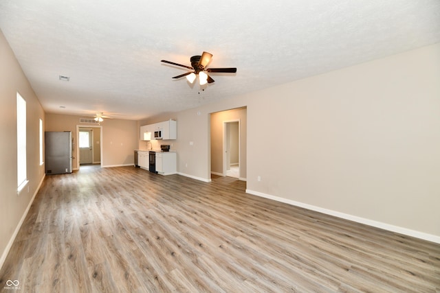 2026 Spruce St, Indianapolis, IN 46203 - unfurnished living room featuring ceiling fan, light wood-type flooring, baseboards, and a textured ceiling