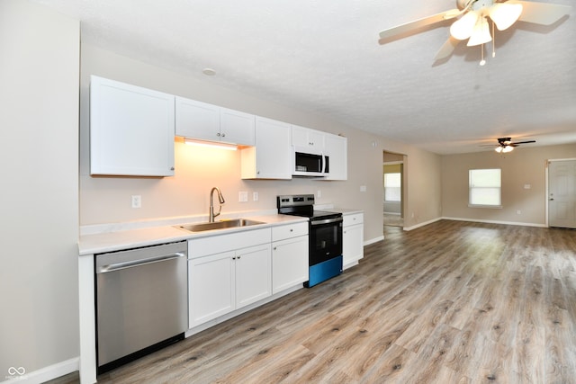 2026 Spruce St, Indianapolis, IN 46203 - kitchen with a sink, appliances with stainless steel finishes, a ceiling fan, white cabinets, and light wood-type flooring