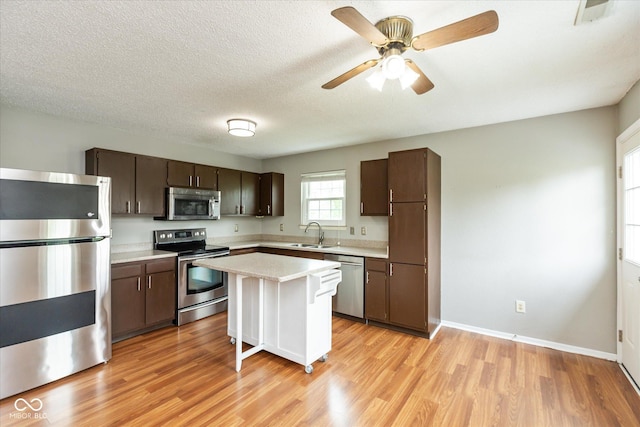 18005 Gasparilla Ct, Westfield, IN 46062 - kitchen with appliances with stainless steel finishes, light countertops, dark brown cabinetry, light wood finished floors, and a textured ceiling