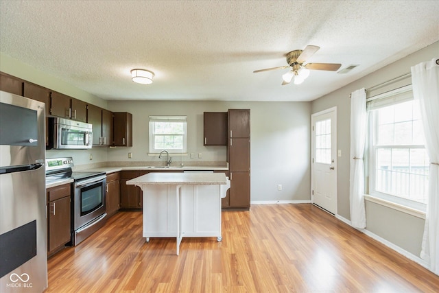 18005 Gasparilla Ct, Westfield, IN 46062 - kitchen featuring appliances with stainless steel finishes, light countertops, light wood-style flooring, dark brown cabinets, and a textured ceiling