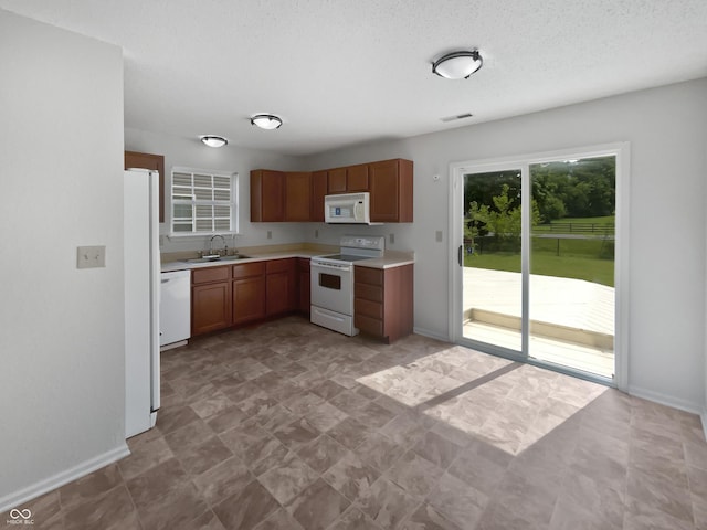 8437 Crosser Dr, Indianapolis, IN 46237 - kitchen featuring white appliances, a sink, light countertops, baseboards, and brown cabinets