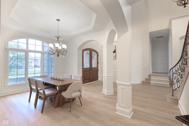 10471 Winghaven Dr, Noblesville, IN 46060 - dining area with a decorative wall, arched walkways, a tray ceiling, light wood-style flooring, and a chandelier
