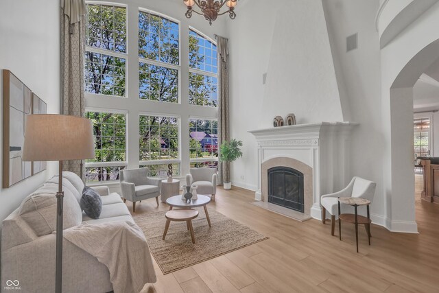 10471 Winghaven Dr, Noblesville, IN 46060 - living room with a high ceiling, arched walkways, wood finished floors, a glass covered fireplace, and a chandelier