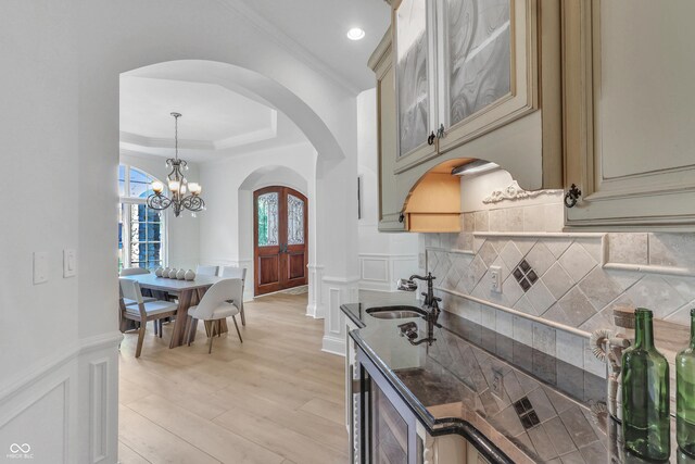 10471 Winghaven Dr, Noblesville, IN 46060 - kitchen with arched walkways, wine cooler, cream cabinets, a decorative wall, and ornamental molding