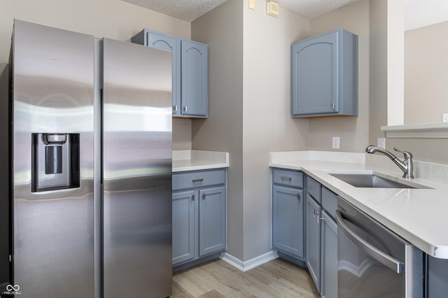 3351 Summer Breeze Cir, Indianapolis, IN 46239 - kitchen featuring stainless steel appliances, light wood-type flooring, a textured ceiling, blue cabinetry, and light countertops