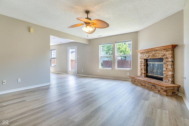 3351 Summer Breeze Cir, Indianapolis, IN 46239 - unfurnished living room featuring a textured ceiling, a glass covered fireplace, a ceiling fan, and wood finished floors