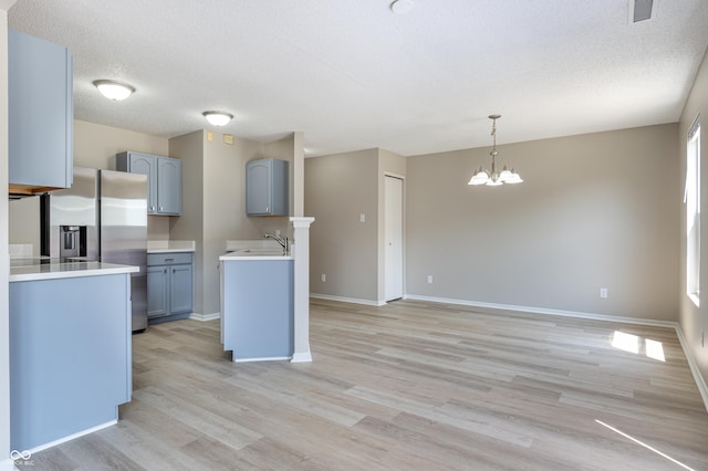 3351 Summer Breeze Cir, Indianapolis, IN 46239 - kitchen featuring stainless steel fridge, light wood-type flooring, a textured ceiling, a chandelier, and pendant lighting