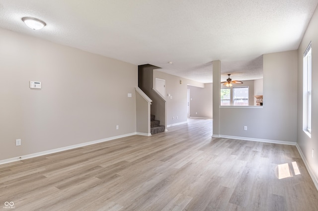 3351 Summer Breeze Cir, Indianapolis, IN 46239 - unfurnished living room featuring light wood finished floors, stairs, ceiling fan, and a textured ceiling