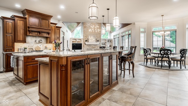 13346 W Sherbern Dr, Carmel, IN 46032 - kitchen featuring a spacious island, crown molding, backsplash, light stone countertops, and hanging light fixtures