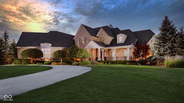 13346 W Sherbern Dr, Carmel, IN 46032 - french provincial home featuring a front lawn, a porch, curved driveway, a chimney, and brick siding