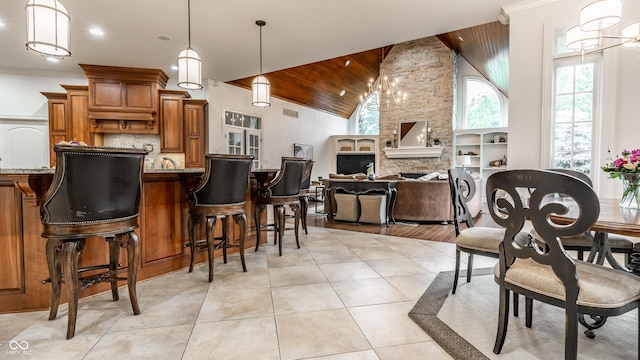 13346 W Sherbern Dr, Carmel, IN 46032 - kitchen with brown cabinets, light stone countertops, decorative light fixtures, a breakfast bar area, and a fireplace