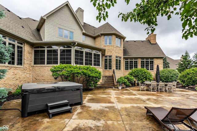 13346 W Sherbern Dr, Carmel, IN 46032 - back of house with a hot tub, a patio, a chimney, and brick siding