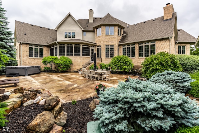 13346 W Sherbern Dr, Carmel, IN 46032 - back of property with a hot tub, a sunroom, a chimney, a patio, and brick siding
