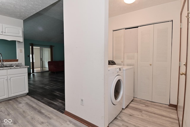 1411 Mimosa Ct, Greenfield, IN 46140 - laundry area featuring washer and clothes dryer, light wood-style floors, cabinet space, and a textured ceiling