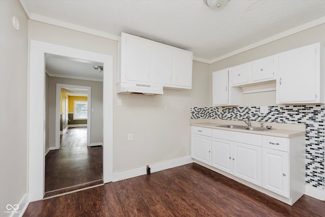 1938 N Dearborn St, Indianapolis, IN 46218 - kitchen with light countertops, dark wood-style flooring, backsplash, white cabinetry, and ornamental molding