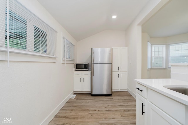 1038 W 33rd St, Indianapolis, IN 46208 - kitchen featuring stainless steel appliances, light wood-style flooring, white cabinetry, lofted ceiling, and light countertops