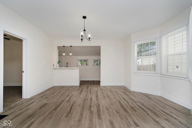 1038 W 33rd St, Indianapolis, IN 46208 - unfurnished living room featuring a chandelier, light wood-style floors, and healthy amount of natural light
