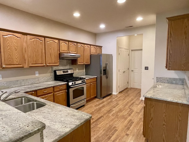 125 Bridgemor Ln, Mooresville, IN 46158 - kitchen with appliances with stainless steel finishes, a sink, under cabinet range hood, light wood finished floors, and brown cabinets