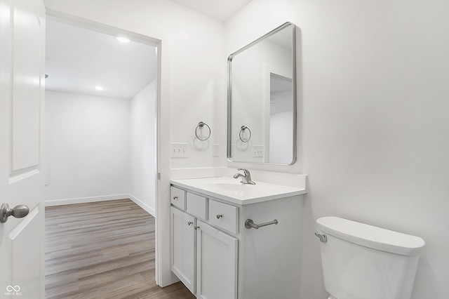 1612 Paula Dr, Columbus, IN 47201 - half bathroom featuring vanity, toilet, wood finished floors, and baseboards