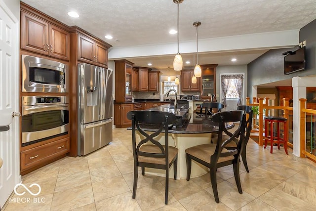 2457 N Centerline Rd, Franklin, IN 46131 - kitchen with appliances with stainless steel finishes, a breakfast bar area, a textured ceiling, decorative light fixtures, and a sink