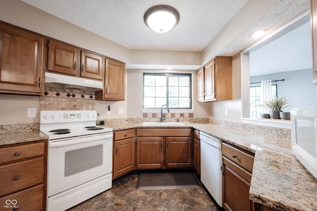 7686 Micawber Ct, Indianapolis, IN 46256 - kitchen featuring white appliances, under cabinet range hood, brown cabinets, backsplash, and stone finish floors