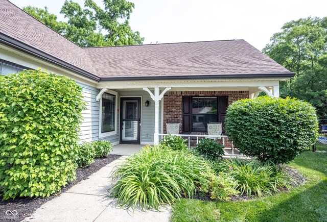7686 Micawber Ct, Indianapolis, IN 46256 - entrance to property with roof with shingles, brick siding, and a porch