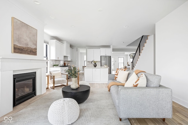 1717 Carrollton Ave, Indianapolis, IN 46202 - living area with stairs, light wood-style flooring, a glass covered fireplace, and recessed lighting