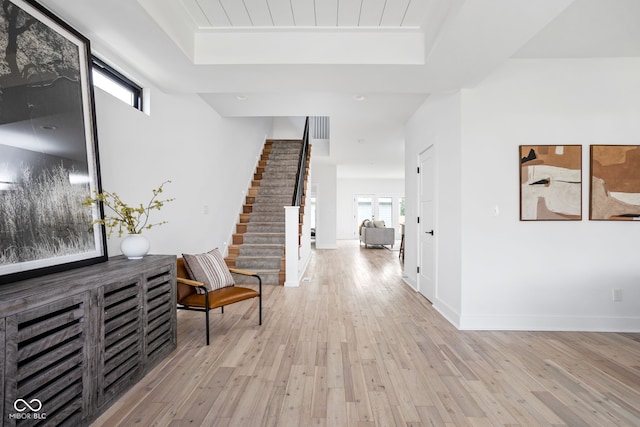 1717 Carrollton Ave, Indianapolis, IN 46202 - hallway featuring a tray ceiling, stairs, and light wood-style flooring