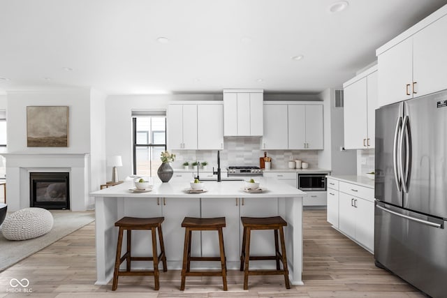 1717 Carrollton Ave, Indianapolis, IN 46202 - kitchen featuring stainless steel appliances, a kitchen breakfast bar, decorative backsplash, a kitchen island with sink, and recessed lighting