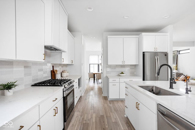1717 Carrollton Ave, Indianapolis, IN 46202 - kitchen with appliances with stainless steel finishes, white cabinetry, tasteful backsplash, light stone countertops, and light wood-type flooring