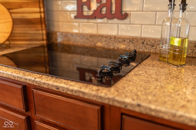 226 S Cave Creek Dr S, Bloomington, IN 47403 - kitchen view of decorative backsplash, light stone counters, and black electric stovetop