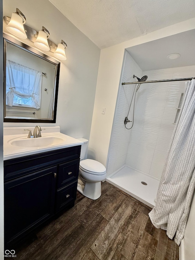 1002 Meadow Ln, Greencastle, IN 46135 - bathroom featuring wood finished floors, vanity, tiled shower, toilet, and a textured ceiling