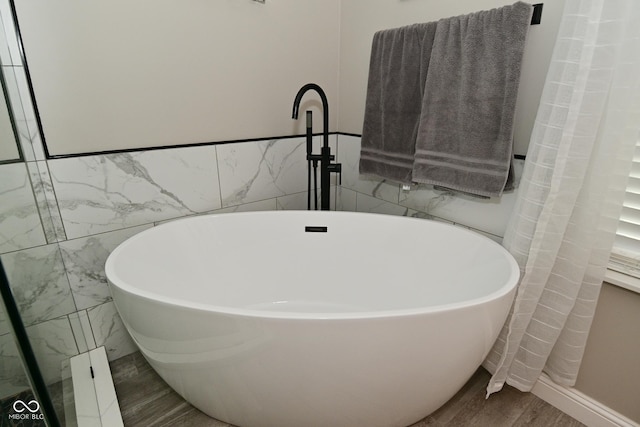 1744 Salina Dr, Avon, IN 46123 - bathroom with tile walls, a freestanding bath, wood finished floors, and a wainscoted wall