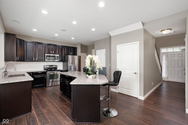 1143 Hampton Dr, Greenwood, IN 46143 - kitchen featuring appliances with stainless steel finishes, dark wood-style flooring, a breakfast bar area, a center island, and light stone counters