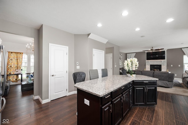 1143 Hampton Dr, Greenwood, IN 46143 - kitchen with ceiling fan, dark wood finished floors, a chandelier, a center island, and a stone fireplace