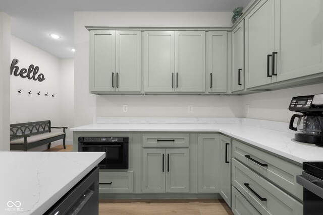 3365 Riverside Dr, Columbus, IN 47203 - kitchen featuring black oven, light stone counters, light wood finished floors, recessed lighting, and gray cabinets