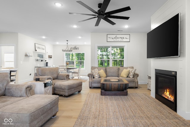 3365 Riverside Dr, Columbus, IN 47203 - living room with light wood finished floors, a chandelier, a glass covered fireplace, recessed lighting, and ceiling fan