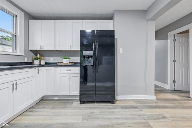 2720 S Taft Ave, Indianapolis, IN 46241 - kitchen featuring black fridge with ice dispenser, light wood-type flooring, dark countertops, and white cabinetry