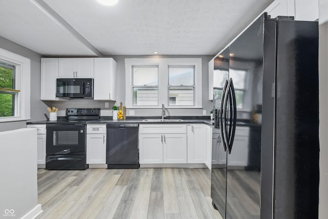 2720 S Taft Ave, Indianapolis, IN 46241 - kitchen featuring black appliances, dark countertops, light wood-style floors, and white cabinets